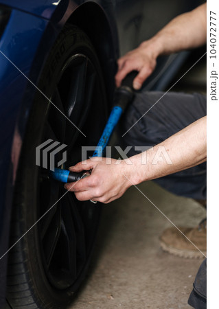 Close-up of mechanic change tires on a car near his garage. Woking outdoors Close-up of mechanic change tires on a car near his garage. Woking outdoors 104072777