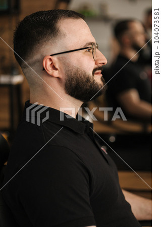 Side view of handsome man in barbershop. Man in glasses with finish hairstyle Side view of handsome man in barbershop. Man in glasses with finish hairstyle 104073581