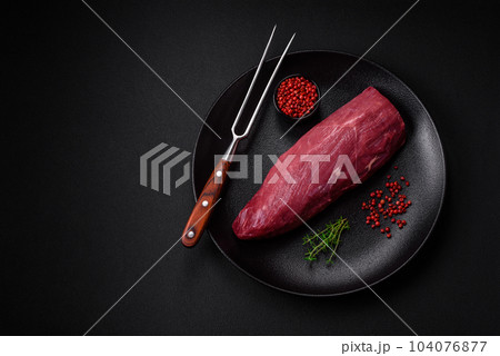 Juicy raw beef with spices, salt and herbs on a dark concrete background 104076877