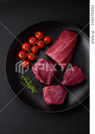 Juicy raw beef with spices, salt and herbs on a dark concrete background Juicy raw beef with spices, salt and herbs on a dark concrete background 104076892