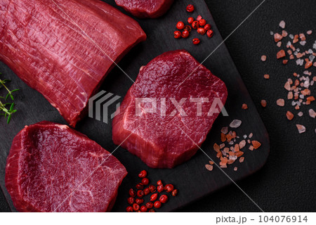 Juicy raw beef with spices, salt and herbs on a dark concrete background 104076914