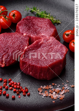 Juicy raw beef with spices, salt and herbs on a dark concrete background Juicy raw beef with spices, salt and herbs on a dark concrete background 104076927