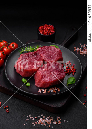Juicy raw beef with spices, salt and herbs on a dark concrete background Juicy raw beef with spices, salt and herbs on a dark concrete background 104076951