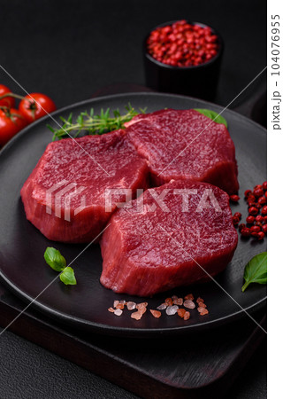 Juicy raw beef with spices, salt and herbs on a dark concrete background Juicy raw beef with spices, salt and herbs on a dark concrete background 104076955