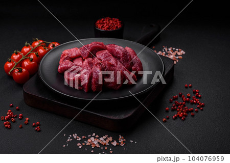 Juicy raw beef with spices, salt and herbs on a dark concrete background 104076959