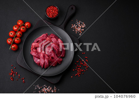 Juicy raw beef with spices, salt and herbs on a dark concrete background Juicy raw beef with spices, salt and herbs on a dark concrete background 104076960