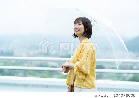 雨天の日にお出かけする女性　傘を持った女性 104078009