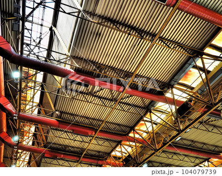 The roof of a hangar, a production hall or a sports hall. Metal structures, beams, supporting elements. Ventilation systems in large halls and rooms. Skylights. Industrial interior The roof of a hangar, a production hall or a sports hall. Metal structures, beams, supporting elements. Ventilation systems in large halls and rooms. Skylights. Industrial interior 104079739