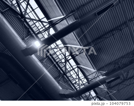 The roof of a hangar, a production hall or a sports hall. Metal structures, beams, supporting elements. Ventilation systems in large halls and rooms. Skylights. Industrial interior The roof of a hangar, a production hall or a sports hall. Metal structures, beams, supporting elements. Ventilation systems in large halls and rooms. Skylights. Industrial interior 104079753