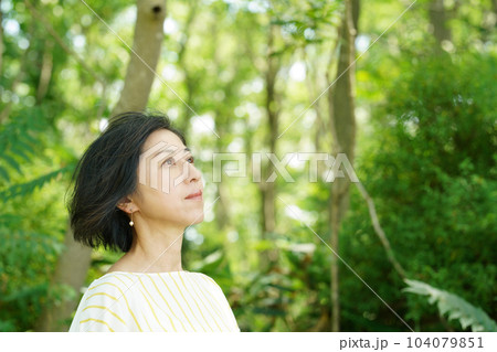 緑の中で風に髪をなびかせる爽やかな中年女性 緑の中で風に髪をなびかせる爽やかな中年女性 104079851
