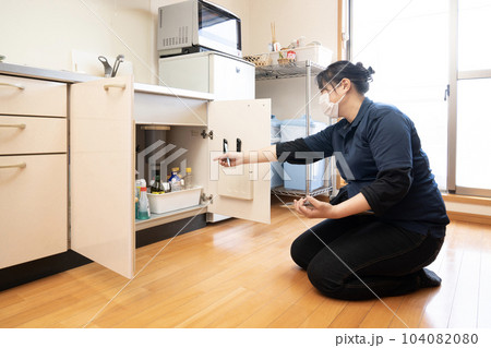 流し台の下の片付けの見積もりをする女性作業員 104082080