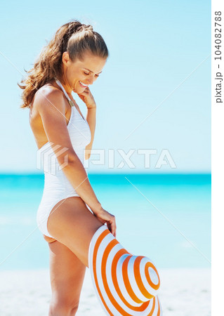 Happy young woman in swimsuit with hat enjoying on beach Happy young woman in swimsuit with hat enjoying on beach 104082788