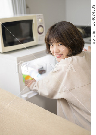 冷蔵庫から飲み物を取り出す若い女性 冷蔵庫から飲み物を取り出す若い女性 104084338