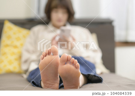 ベッドでスマホを見る若い女性 104084339