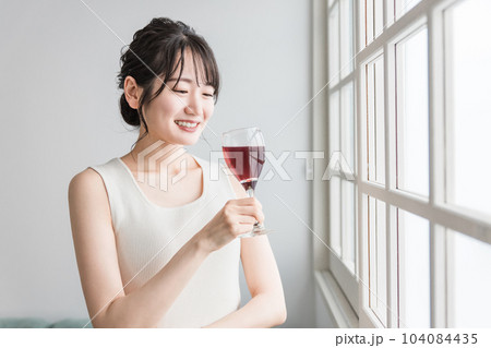 家で赤い飲み物を昼飲みするアジア人女性(赤ワイン・アセロラ・ザクロ・シソ・ポリフェノール・タンニン) 家で赤い飲み物を昼飲みするアジア人女性(赤ワイン・アセロラ・ザクロ・シソ・ポリフェノール・タンニン) 104084435