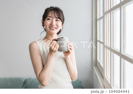 保温マグカップで朝、家でお茶・白湯を飲むリラックスするアジア人女性（温活） 104084441