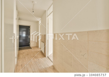 an empty room with wood flooring and white trim on the walls there is a black door in the corner an empty room with wood flooring and white trim on the walls there is a black door in the corner 104085737