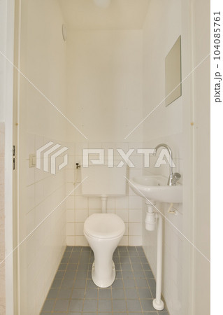 a bathroom that is white and has blue tiles on the floor, with a toilet in the corner next to the sink a bathroom that is white and has blue tiles on the floor, with a toilet in the corner next to the sink 104085761