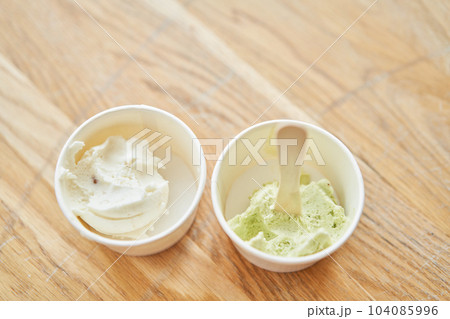 Vanilla and pistachio ice-cream. Ice cream in two disposable cups on the table. Italian gelateria. Natural fresh gelato. Vanilla and pistachio ice-cream. Ice cream in two disposable cups on the table. Italian gelateria. Natural fresh gelato. 104085996