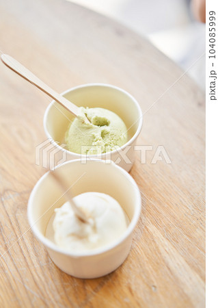Vanilla and pistachio ice-cream. Ice cream in two disposable cups on the table. Italian gelateria. Natural fresh gelato. Vanilla and pistachio ice-cream. Ice cream in two disposable cups on the table. Italian gelateria. Natural fresh gelato. 104085999