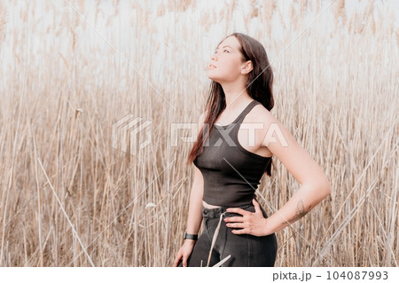 Happy young smiling woman with freckles outdoors portrait. Soft sunny colors. Outdoor close-up portrait of a young brunette woman and looking to the camera, posing against autumn nature background 104087993