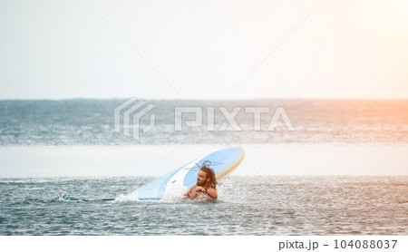 Sea woman and man on sup. Silhouette of happy young woman and man, surfing on SUP board, confident paddling through water surface. Idyllic sunset. Active lifestyle at sea or river. 104088037