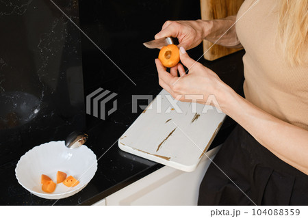 Closeup of woman cutting apricot into halves 104088359