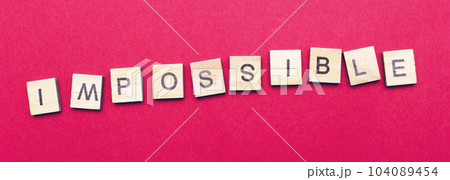 Impossible word made by wooden cubes isolated on pink paper background. Business problem comcept Impossible word made by wooden cubes isolated on pink paper background. Business problem comcept 104089454