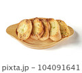 Several slices of garlic bread were placed on a wooden plate. 104091641