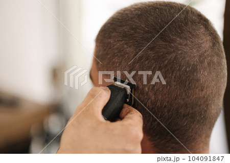 Close-up of human hand hold trimmer and make hairstyle for man. Barbershop Close-up of human hand hold trimmer and make hairstyle for man. Barbershop 104091847