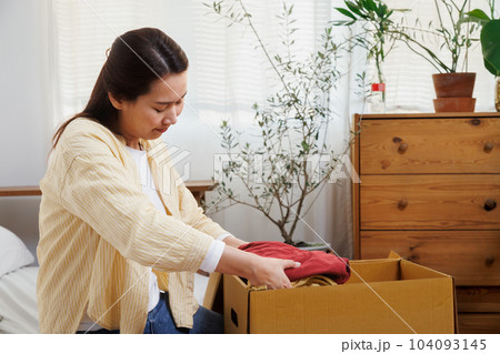volunteer asian woman putting unused clothes into cardboard boxes for donation and charity. Reuse, recycle, renewable and sustainability concept. volunteer asian woman putting unused clothes into cardboard boxes for donation and charity. Reuse, recycle, renewable and sustainability concept. 104093145