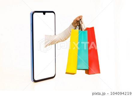 Hands with paper shopping bags outstreched from cellphone screen towards copy space, white background, isolated. Creative image for delivery service mobile application concept Hands with paper shopping bags outstreched from cellphone screen towards copy space, white background, isolated. Creative image for delivery service mobile application concept 104094219