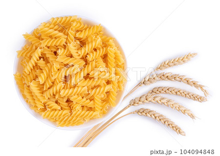 Raw pasta fusilli in bowl and wheat spikelets isolated on white background 104094848