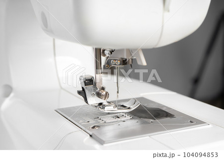 Modern white sewing machine presser foot closeup, macro Modern white sewing machine presser foot closeup, macro 104094853