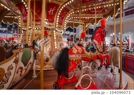 Old French carousel in a holiday park. Three horses and airplane on a traditional fairground vintage carousel. Merry-go-round with horses. Old French carousel in a holiday park. Three horses and airplane on a traditional fairground vintage carousel. Merry-go-round with horses. 104096073