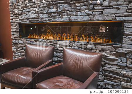 Beautiful luxury interior design with a long fireplace and sofas. Luxury hotel interior design. Beautiful luxury interior design with a long fireplace and sofas. Luxury hotel interior design. 104096182