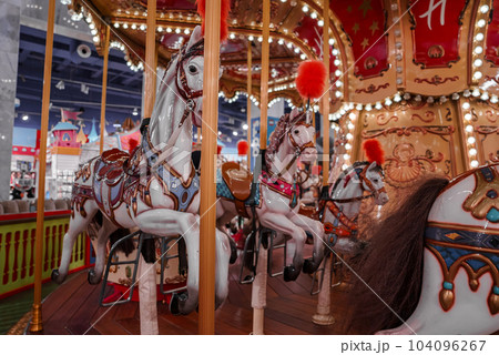 Old French carousel in a holiday park. Three horses and airplane on a traditional fairground vintage carousel. Merry-go-round with horses. 104096267