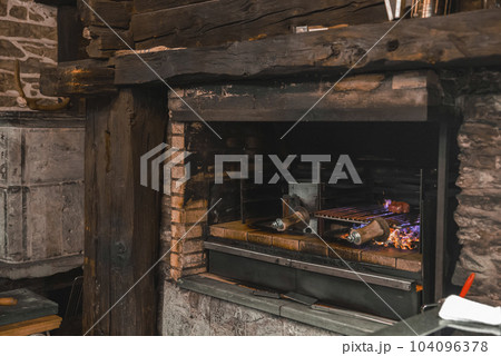Fresh meat cooking in wood fired oven at commercial restaurant kitchen in luxurious alpine hotel, luxury travel concept for tourists 104096378