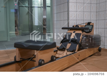 Wooden rowing machine on hardwood floor with tiled wall in exercise room at luxury hotel, luxury travel and fitness concept for tourists 104096708