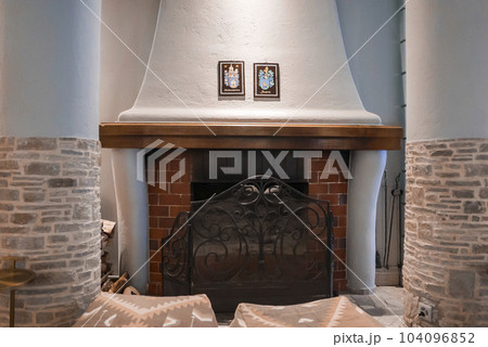 Empty ottomans in front of fireplace between columns in luxurious room at modern hotel, luxury travel concept for tourists 104096852