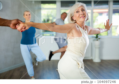 African-American man dances steamy salsa with elderly female companion for fitness classes African-American man dances steamy salsa with elderly female companion for fitness classes 104097246