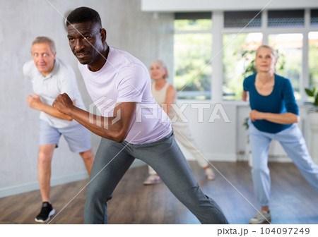 Mature men and women practicing Hip-hop dance in training hall 104097249