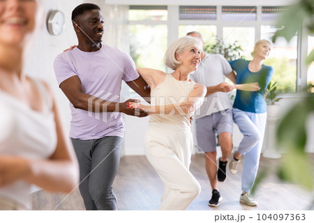 African-American man dances steamy salsa with elderly female companion for fitness classes African-American man dances steamy salsa with elderly female companion for fitness classes 104097363