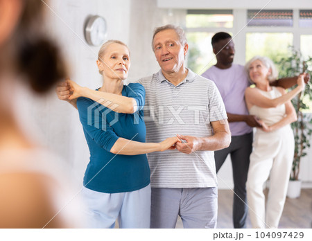 Mature male novice student of fitness studio practices paired Latin American rumba dance 104097429