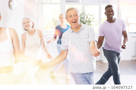 Elderly man learning dynamic dances during group class Elderly man learning dynamic dances during group class 104097527