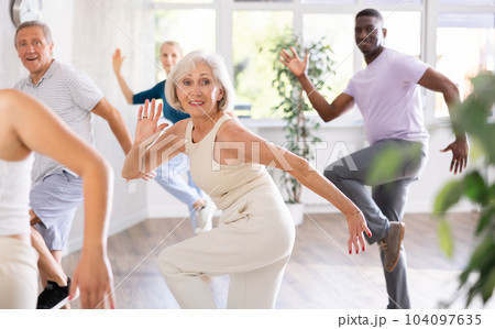 Elderly woman learning modern dynamic dances during group class 104097635