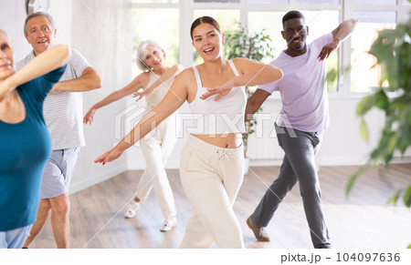 Female instructor teaches mature students of dance class basic movements of hip hop dance 104097636