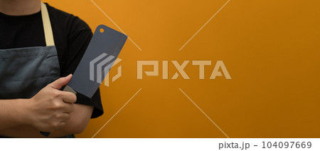 Cropped shot of chef wearing apron holding knifes isolated on yellow background with copy space 104097669