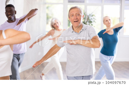Elderly man practicing vigorous dance during group class Elderly man practicing vigorous dance during group class 104097670