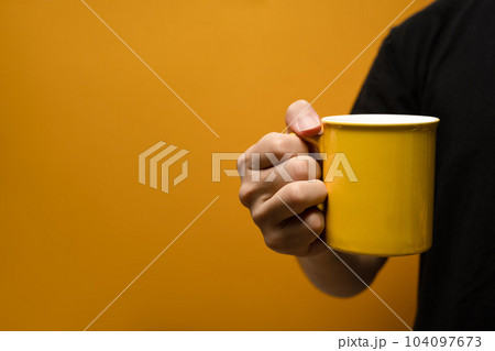 Man holding coffee cup over yellow background. Close up, mockup image, copy space for text Man holding coffee cup over yellow background. Close up, mockup image, copy space for text 104097673